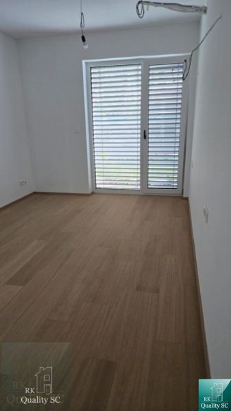 Okr. Senec - Tureň - NA PREDAJ nízkoenergetická novostavba - 4 izbový  - Prázdna izba s podlahou s dreveným dekorom a balkónovými dverami v rodinnom dome.