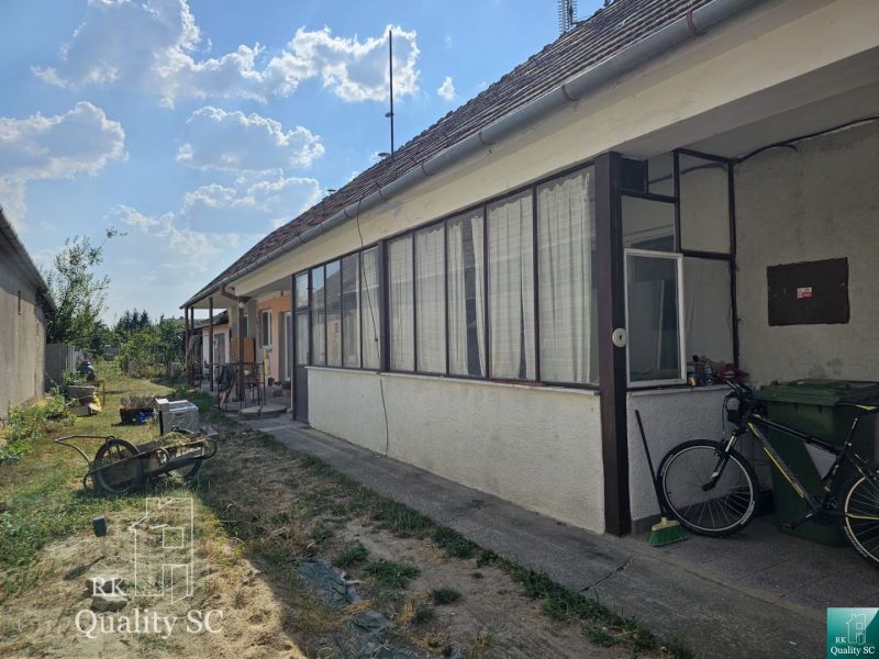 Okres Trnava- obec Pavlice – nehnuteľnosť s potenciálom - 4 izb. RD v  - Dvor rodinného domu v Pavliciach s prístreškom a bicyklom, obklopený trávnikom.