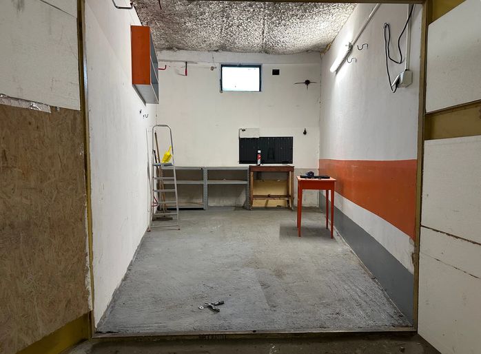 PREDAJ - Garáž na s pozemkom na Pionierskej ulici  - Priestor garáže s betónovou podlahou a pracovným stolom vo vnútri.
