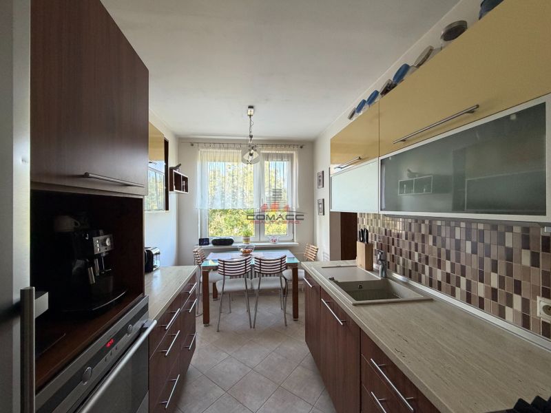 Ex. Moderný 4 iz byt po komplet. rekonštrukcii s lodžiou v Piešťanoch - Kuchyňa so svetlým stolom a podlahou s dreveným dekorom v 4-izbovom byte.