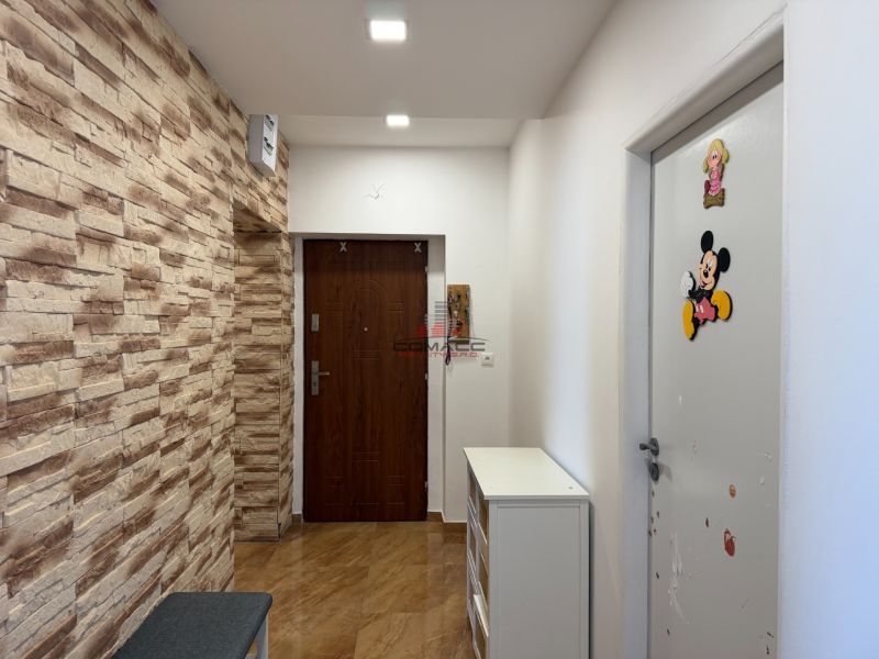Ex. Moderný 3 iz. byt 90 m2 s garážou a záhradou v Dolnom Trhovišti - Chodba v 3-izbovom byte s dekoratívnou kamennou stenou a dvermi s nálepkami.