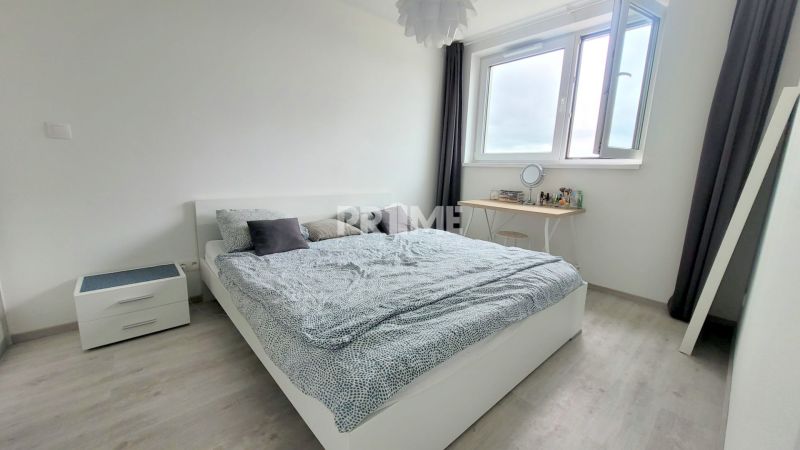 MODERNÝ 2i byt, MATADORKA, BALKÓN, CHLADENIE, PARKING, Závodu Matador - Spálňa so svetlou posteľou, nočný stolík, podlaha s dreveným dekorom, okno s výhľadom.