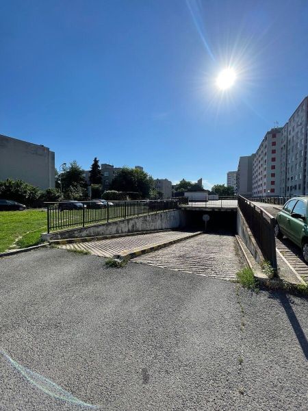 PREDAJ - Garáž na Mierovej ulici - Garáže na Mierovej ulici v Bratislave - Ružinove, obklopené panelákmi, pod modrou oblohou.