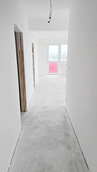 Novostavba - 3- izb. byt s 2 balkónmi a garáž. na ul. Jána Ondruša - Chodba v 3-izbovom byte s bielymi stenami a veľkým oknom na konci.