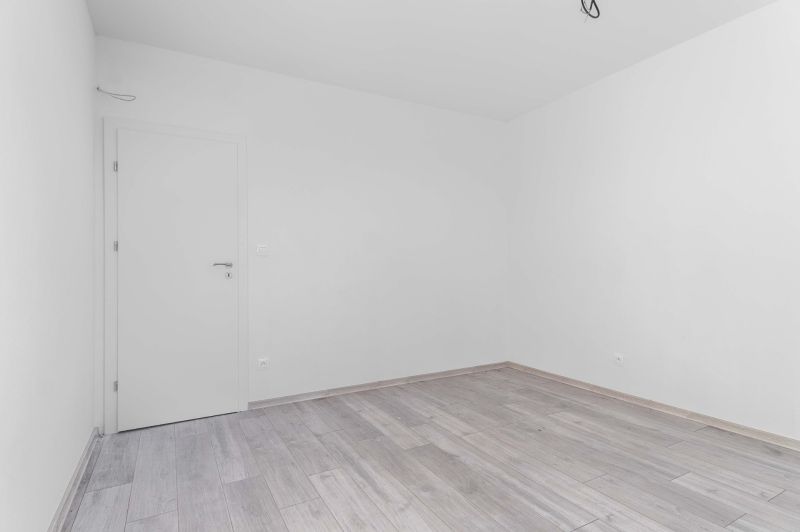 I PREDAJ novostavba 4i rodinného domu s terasou a záhradkou - Prázdna miestnosť s bielymi stenami a podlahou s dreveným dekorom v rodinnom dome.