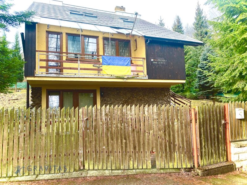 Rekreačný RD pri Oravskej Priehrade na Slanickej Osade - Rodinný dom s dreveným plotom, balkónom, v lesnatom prostredí, výrazné rodinné bývanie.