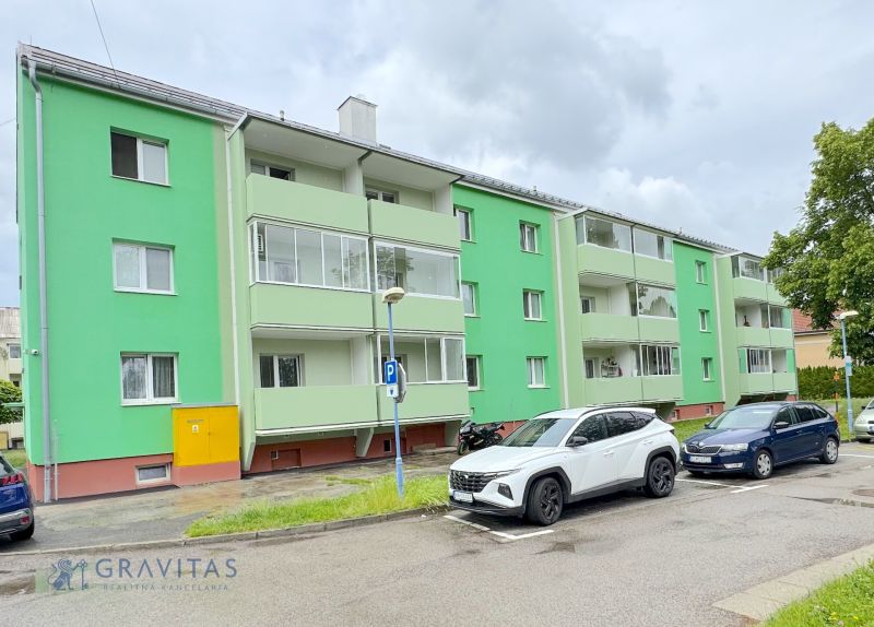 Na predaj 1-izbový byt Bratislavská ul., Dubnica Nad Váhom - Svetlozelený bytový dom na Bratislavskej ulici v Dubnici nad Váhom, zaparkované autá vpredu.