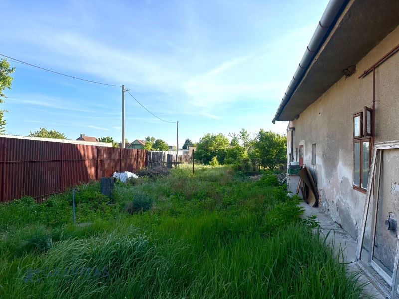 Na predaj investičný pozemok s domom - Exteriér rodinného domu v meste Reca, neudržiavaná záhrada pri budove.