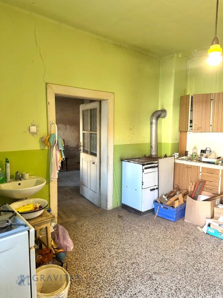 Na predaj investičný pozemok s domom - Kuchyňa v rodinnom dome so starším sporákom a miskou na riad.
