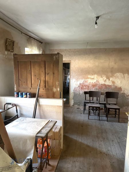Na predaj investičný pozemok s domom - Interiér rodinného domu s neopravovanými stenami, dreveným nábytkom a podlahou s dreveným dekorom.