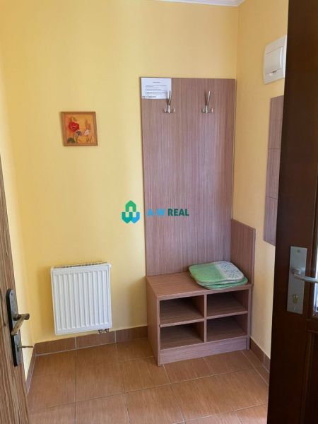 Apartmánový dom na predaj blízko termálneho kúpaliska - Interiér hotelovej izby s vešiakovou stenou, skrinkou a radiátorom.