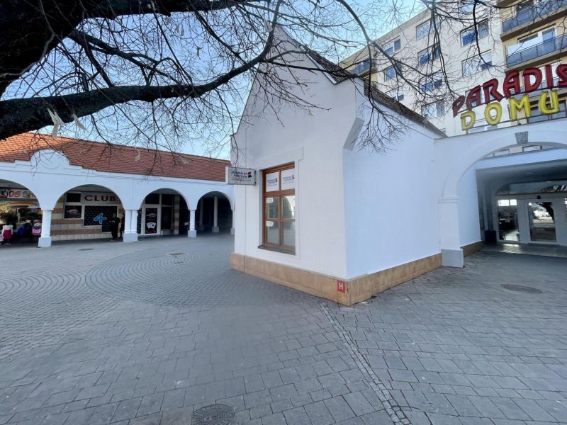 DUNASJKÁ STREDA – OBCHODNÝ/ADMINISTRATÍVNY PRIESTOR PRIAMO V CENTRE ME - Obchodné priestory na Námestí Ármina Vámberyho v Dunajskej Strede s arkádami a stromami.