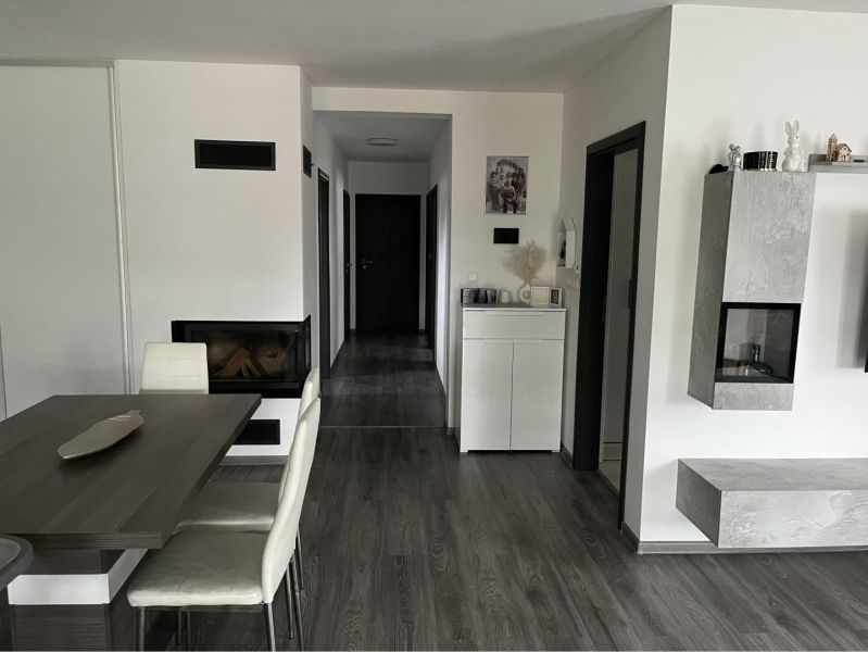 HORNÁ POTOŇ – 4-IZBOVÝ RODINNÝ DOM - NOVOSTAVBA - Interiér rodinného domu s podlahou s dreveným dekorom, jedálenským stolom a krbom.