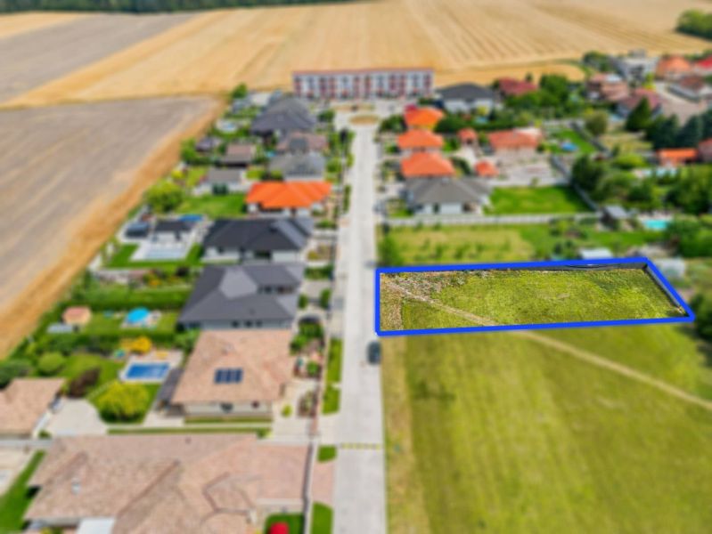 Stavebný pozemok v novej štvrti obce Ohrady – 969 m² - Letecký pohľad na pozemky pre bývanie v Ohradoch lemované domami s dvormi.