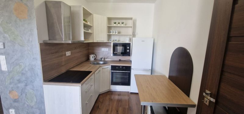 2-IZBOVÝ BYT S VEĽKÝM BALKÓNOM NA PREDAJ - Kuchyňa v 2-izbovom byte so spotrebičmi a podlahou s dreveným dekorom.