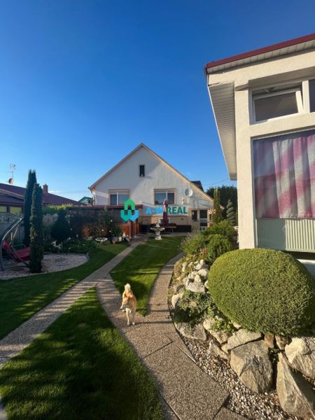 Znížená cena!  Rodinný dom s vnútorným aj vonkajším bazénom na krásne  - Rodinný dom v Orechovej Potôni s udržiavanou záhradou, chodníkom a psom pobehujúcim po trávniku.