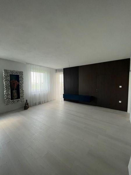 Luxusný byt na prenájom úplne nový kompletne zariadený s garážou. - Obývacia izba s podlahou s dreveným dekorom, závesmi a dekoratívnym zrkadlom v 3-izbovom byte.