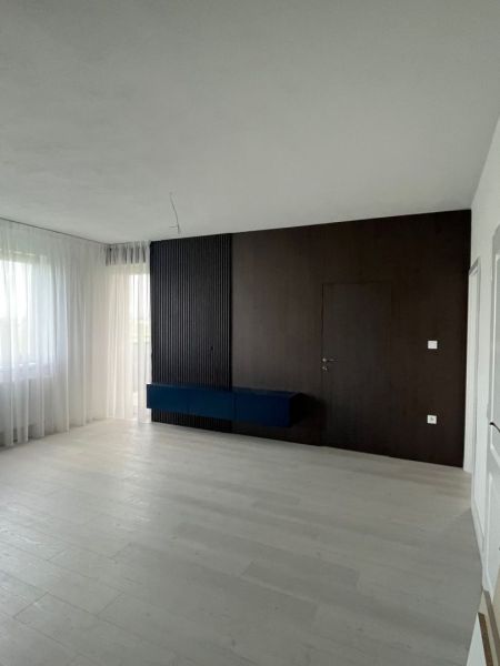 Luxusný byt na prenájom úplne nový kompletne zariadený s garážou. - Obývacia izba s tmavou stenou a podlahou s dreveným dekorom v 3-izbovom byte.