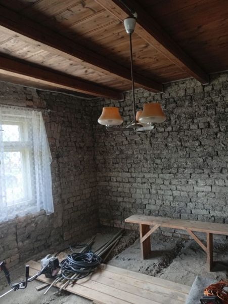 Vidiecky domček na predaj. - Miestnosť s tehlovými stenami, dreveným stropom a jednoduchým osvetlením v rodinnom dome.