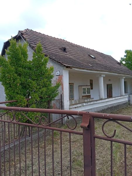 Vidiecky domček na predaj. - Rodinný dom v Ňárade so šikmou strechou, stĺpmi a viditeľným plotom, obklopený zeleňou.