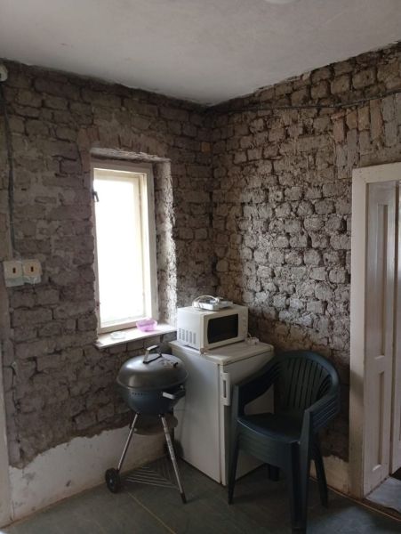 Vidiecky domček na predaj. - Miestnosť s tehlovými stenami, grilom, mikrovlnkou a plastovou stoličkou v rodinnom dome.