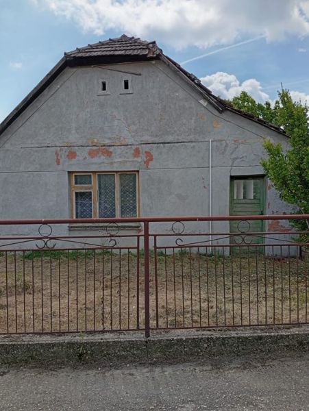 Vidiecky domček na predaj. - Rodinný dom v Ňárade so starou fasádou, plotom a zatvorenými oknami.