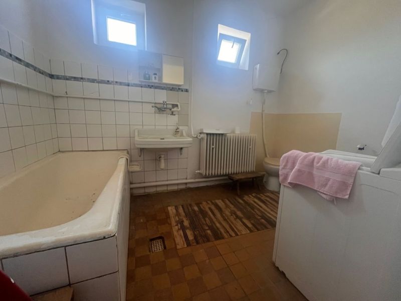 Rodinný dom okamžite obývateľný. - Kúpeľňa v rodinnom dome s vaňou, umývadlom a práčkou, má dlažbu i radiátor.
