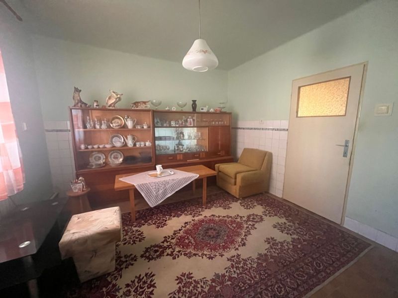 Rodinný dom okamžite obývateľný. - Obývacia izba v rodinnom dome s vitrínou, kobercami a zelenými stenami.