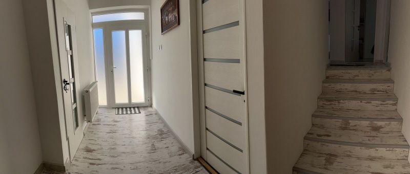 Ůžasný rodinný dom v obci Trstice. - Chodba rodinného domu s podlahou s dreveným dekorom a svetlými dverami.
