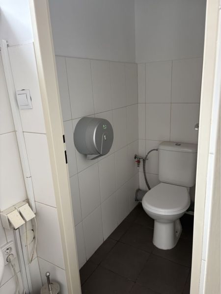 Prenájom nebytového priestoru na podnikateľské účely v CENTRE Dunajske - Toaleta v budove so svetlými obkladačkami a tmavou podlahou.