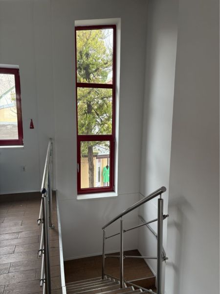 Prenájom nebytového priestoru na podnikateľské účely v CENTRE Dunajske - Schodisko v budove s oknami s červeným rámom a podlahou s dreveným dekorom.