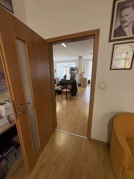 Znížená cena!!☎️ - Interiér s podlahou s dreveným dekorom a otvorenými dverami vedúci do kancelárie.