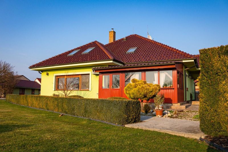 Úžasný veľkometrážny 7-izbový rodinný dom v obci Dolný Bar - Rodinný dom v Dolnom Bare so zeleňou a živým plotom, terasa a škridlová strecha.