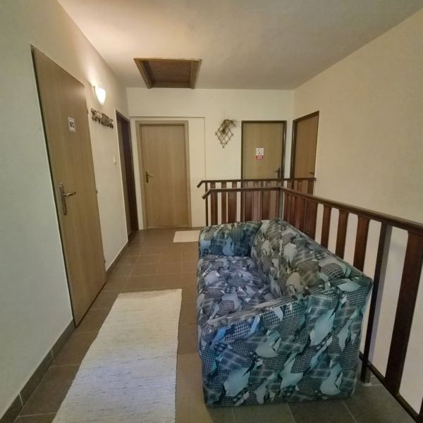Prenájom 2-izbového apartmánu v Dunajskej Strede - Chodba so sedačkou, tromi dverami a schodiskovým zábradlím v 2-izbovom byte.
