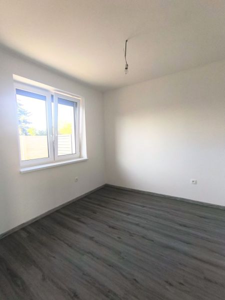 Výrazná zľava do konca októbra - 3izbový rodinný dom v obci Orechová P - Biela miestnosť s oknom a podlahou s dreveným dekorom v rodinnom dome.