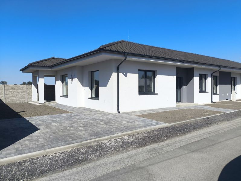 Moderný 4-izbový rodinný dom (dvojdom) v obci Vrakúň - Rodinný dom vo Vrakúni s bielou fasádou, vydláždeným chodníkom a betónovým plotom.