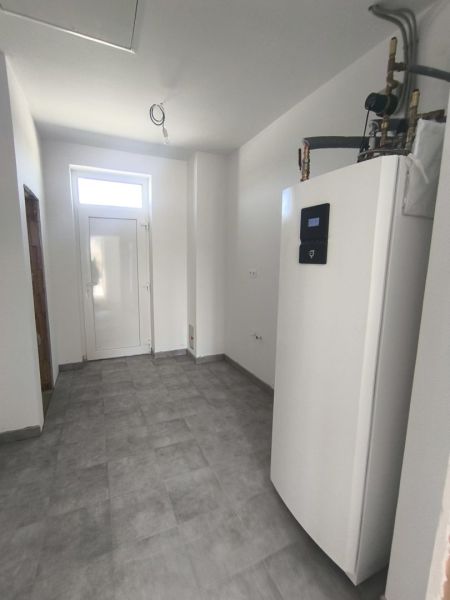 Moderný 4-izbový rodinný dom (dvojdom) v obci Vrakúň - Technická miestnosť v rodinnom dome s tepelným čerpadlom a sivou podlahou.