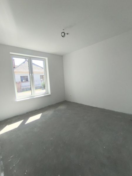 Moderný 4-izbový rodinný dom (dvojdom) v obci Vrakúň - Prázdna izba v rodinnom dome s betónovou podlahou a veľkým oknom.
