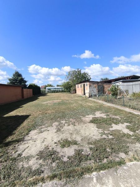 EXKLUZÍVNE LEN U NÁS! 4-izbový rodinný dom v obci Vydrany - Záhrada rodinného domu vo Vydranoch, budovy a kríky pod modrou oblohou.
