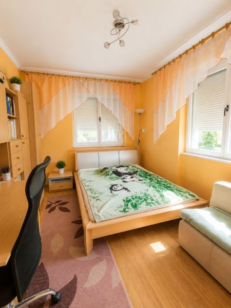 EXKLUZÍVNE LEN U NÁS! 4-izbový rodinný dom v obci Vydrany - Spálňa s posteľou, stolom, policou a podlahou s dreveným dekorom v rodinnom dome.