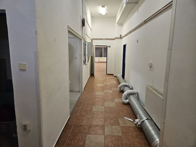 Exkluzívny obchodný priestor na predaj v centre Dunajskej Stredy – ul. - Chodba so svetlými stenami, dlažbou a potrubím v obchodných priestoroch.