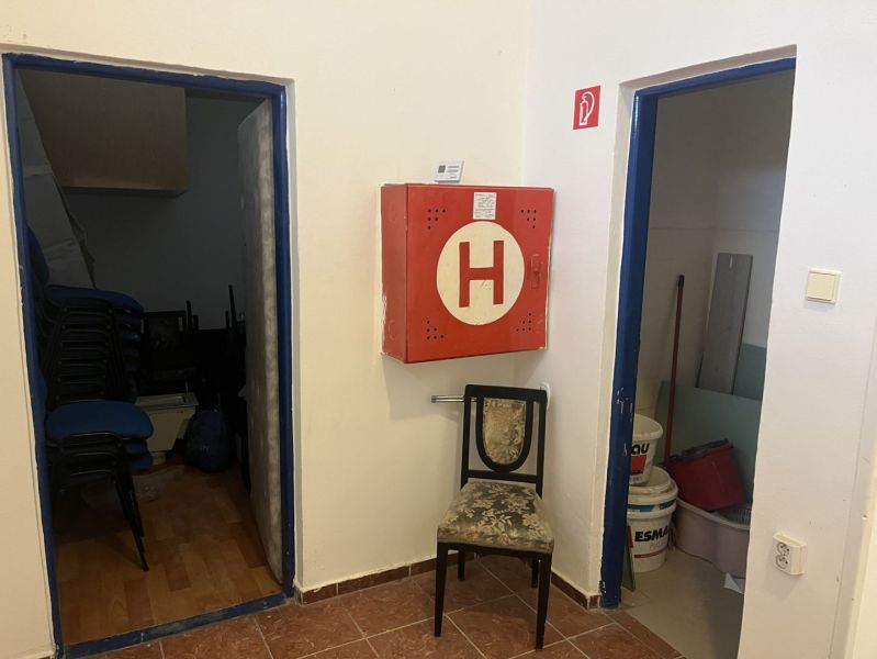 Exkluzívny obchodný priestor na prenájom v centre Dunajskej Stredy – u - Interiér obchodných priestorov s hasičskou skriňou, stoličkou a skladovacími miestnosťami.