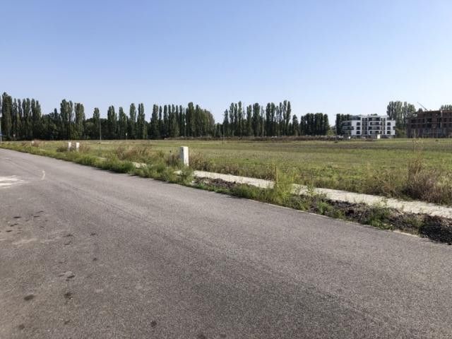 Exkluzívny stavebný pozemok 579 m² – Dunajská Streda, Florida Park - Cesta pri pozemkoch na bývanie v Dunajskej Strede, obklopená zeleňou a budovami.