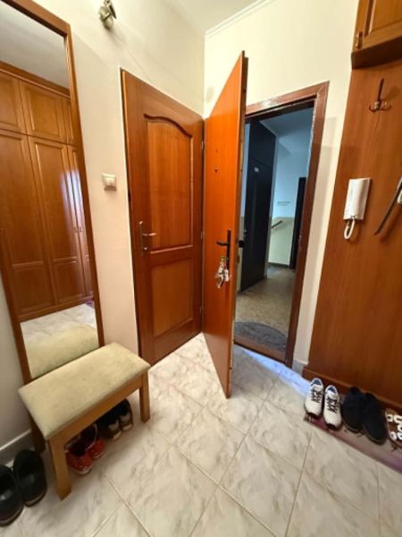 Klasika, ktorá sa neodmieta - Predsieň 3-izbového bytu s bielou dlažbou a dreveným dekorom skríň.
