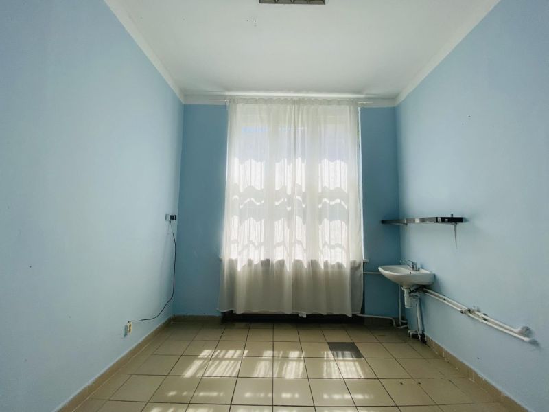 -Na prenájom obchodný priestor 30 m2 v centre mesta Dunajská Streda - Izba s modrými stenami, umývadlom a dlažbou, svetlo preniká cez záclonu.