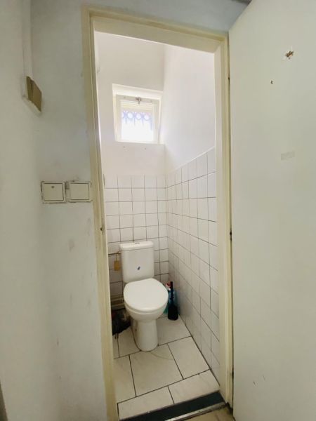 -Na prenájom obchodný priestor 30 m2 v centre mesta Dunajská Streda - Toaleta s dlaždicami na stenách a malým oknom v obchodných priestoroch.