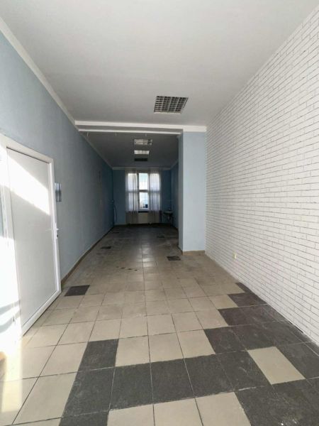-Na prenájom obchodný priestor 30 m2 v centre mesta Dunajská Streda - Úzke obchodné priestory s dlažbou, modrými stenami a tehlovým dekorom steny.