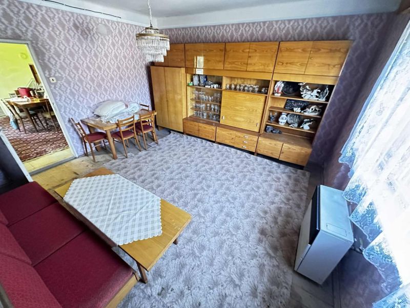 Na predaj starší rodinný dom vhodný na kompletnú prestavbu s  veľkým p - Obývacia izba v rodinnom dome s nábytkom a kobercom, podlaha s dreveným dekorom.