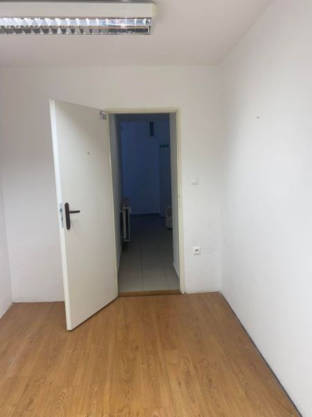 -Na prenájom menší priestor v suteréne  v srdci  mesta Dunajskej Stred - Kancelárie s podlahou s dreveným dekorom a otvorenými dverami.