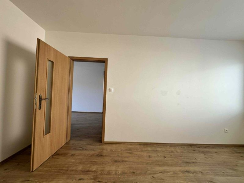 NA PREDAJ MODERNÝ 3-IZBOVÝ BYT S TERASOU V CENTRE DUNAJSKEJ STREDY – P - Izba v 3-izbovom byte s podlahou s dreveným dekorom a bielymi stenami.